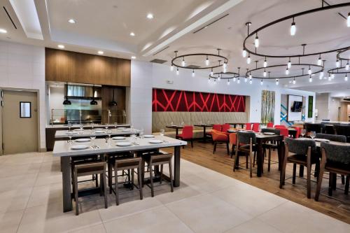 a kitchen and dining room with tables and red chairs at Hilton Garden Inn Bel Air, Md in Bel Air