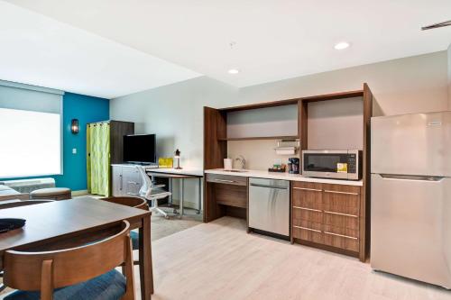 a kitchen with a table and a refrigerator at Home2 Suites By Hilton Bloomington Normal in Normal