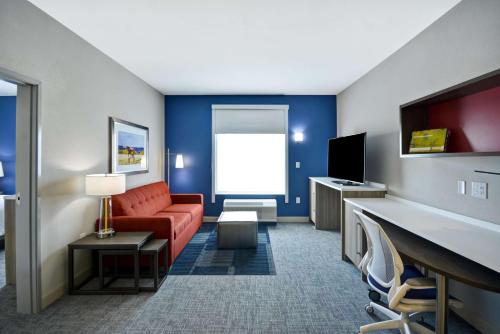 a hotel room with a couch and a tv at Home2 Suites By Hilton Bloomington Normal in Normal