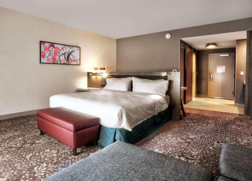 um quarto de hotel com uma cama grande e um banco vermelho em Hilton Garden Inn Bel Air, Md em Bel Air