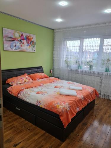 1 dormitorio con 1 cama grande con edredón de naranja en Apartament modern-nou Cristina&Jessica, en Mediaş