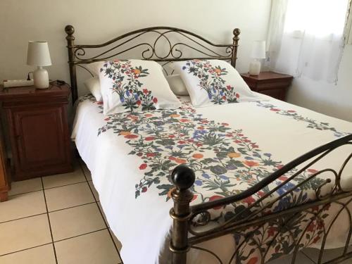 un letto con copriletto e cuscini floreali; di Les Capucines a Saint-Pierre