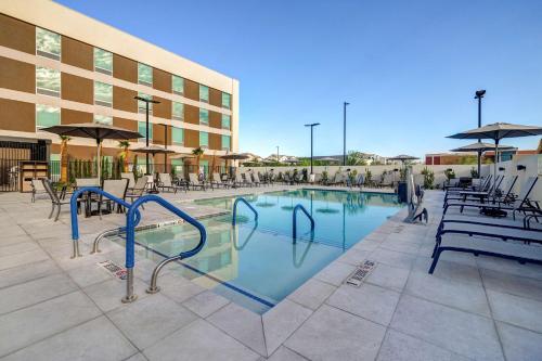 a swimming pool with chairs and a building at Home2 Suites By Hilton Las Vegas Northwest in Las Vegas