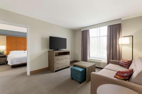 a hotel room with a couch and a flat screen tv at Homewood Suites By Hilton Carlisle in Carlisle