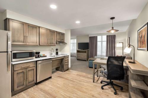 a kitchen with wooden cabinets and a desk with a chair at Homewood Suites By Hilton Carlisle in Carlisle