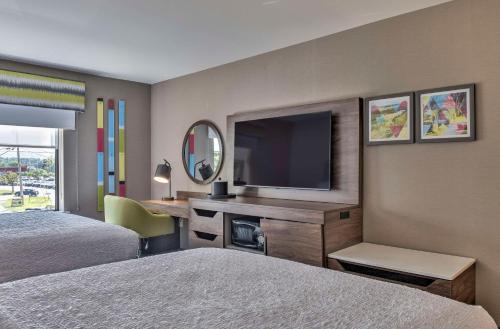 a hotel room with two beds and a flat screen tv at Hampton Inn & Suites Keene in Keene