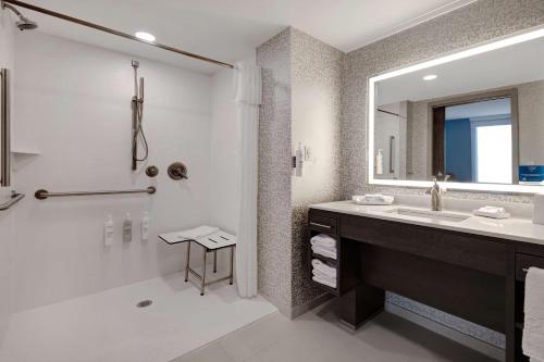 a bathroom with a shower and a sink and a mirror at Home2 Suites By Hilton Wilkes-Barre in Wilkes-Barre