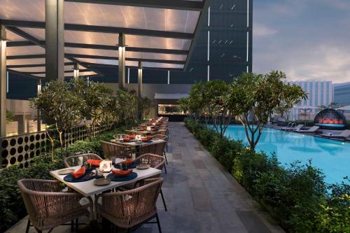 a row of tables and chairs on a building with a pool at Hilton Bengaluru Embassy Manyata Business Park in Bengaluru