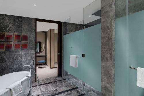 a bathroom with a tub and a glass wall at Hilton Bengaluru Embassy Manyata Business Park in Bengaluru