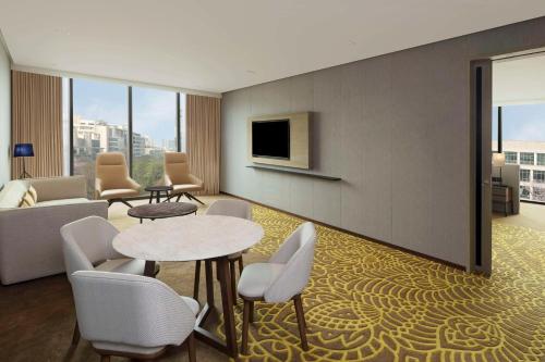 a hotel room with tables and chairs and a tv at Hilton Bengaluru Embassy Manyata Business Park in Bengaluru