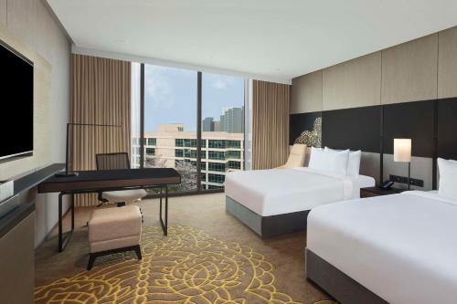 a hotel room with two beds and a desk and a television at Hilton Bengaluru Embassy Manyata Business Park in Bangalore