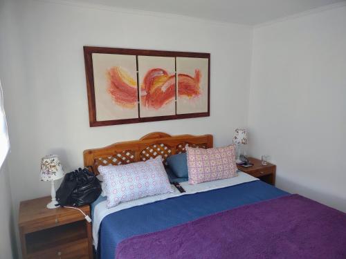 バルパライソにあるMaitencillo Cerca de la Playaのベッドルーム1室(ベッド1台付)が備わります。壁に2枚の写真が飾られています。