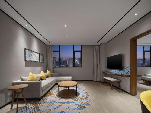 a living room with a couch and a tv at Hilton Garden Inn Jincheng Gushuyuan in Jincheng