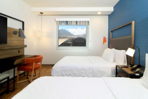a hotel room with two beds and a desk and a window at Tru By Hilton Monterrey Fundidora in Monterrey