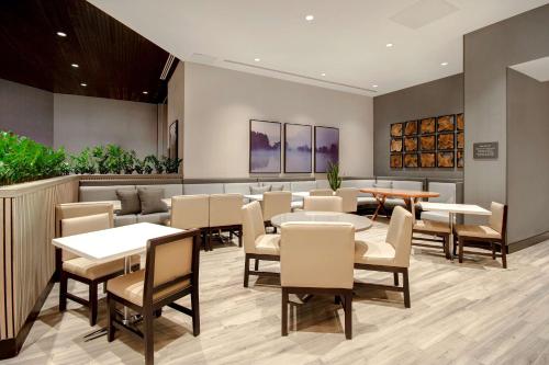 a restaurant with tables and chairs and plants at Embassy Suites By Hilton Alpharetta Halcyon in Alpharetta