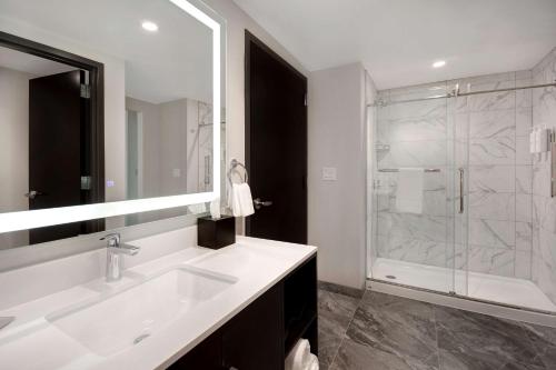 a white bathroom with a sink and a shower at Embassy Suites By Hilton Alpharetta Halcyon in Alpharetta