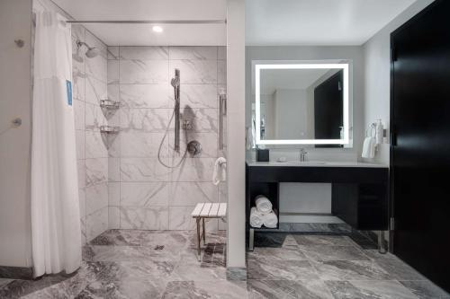 a bathroom with a shower and a sink and a mirror at Embassy Suites By Hilton Alpharetta Halcyon in Alpharetta