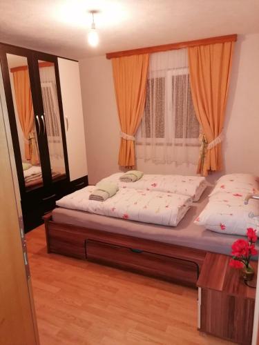 Apartman Natur في يايتشه: غرفة نوم بسريرين مع ستائر برتقالية