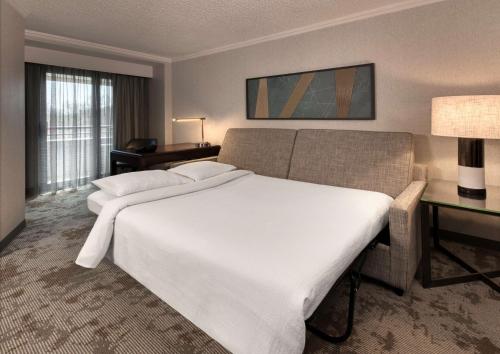 a hotel room with a large white bed and a desk at Embassy Suites by Hilton Bethesda Washington DC in Bethesda
