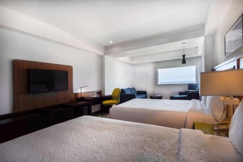 a hotel room with two beds and a flat screen tv at Hampton by Hilton Veracruz Boca Del Rio in Veracruz