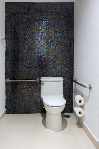 a bathroom with a toilet and a mosaic wall at Hampton by Hilton Veracruz Boca Del Rio in Veracruz