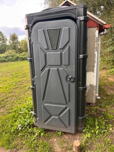 a large metal box with a door in a field at V dedine a predsa mimo nej v maringotke na samote in Dechtice