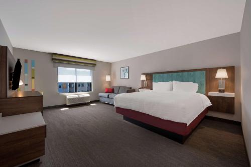 a large hotel room with a bed and a couch at Hampton Inn by Hilton Detroit Southfield in Southfield