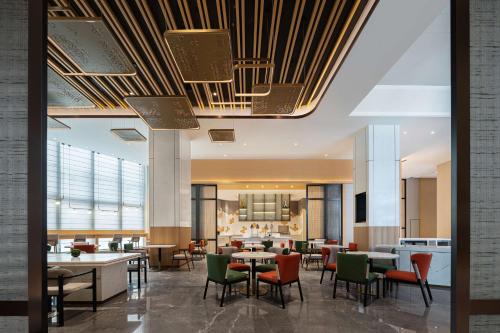 a restaurant with tables and chairs in a lobby at Hilton Garden Inn Changsha Yuelu in Changsha