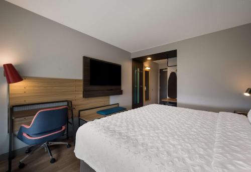 a bedroom with a bed and a desk and a television at Tru By Hilton Novi Detroit in Novi