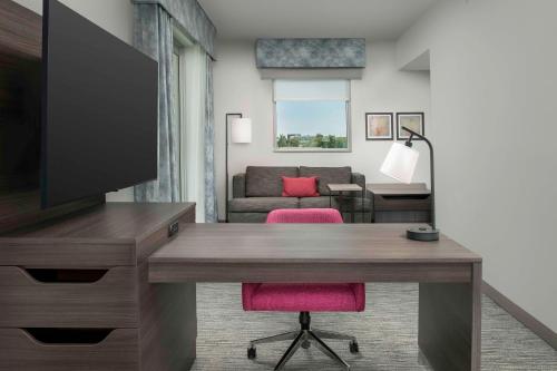 a room with a desk with a television and a living room at Hampton Inn Delray Beach in Delray Beach