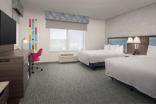 a hotel room with two beds and a flat screen tv at Hampton Inn Delray Beach in Delray Beach