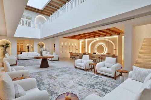 una gran sala de estar con muebles blancos y una escalera. en Maysan Doha, LXR Hotels & Resorts, en Doha