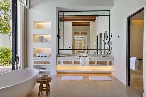 a bathroom with a tub and a large mirror at Maysan Doha, LXR Hotels & Resorts in Doha