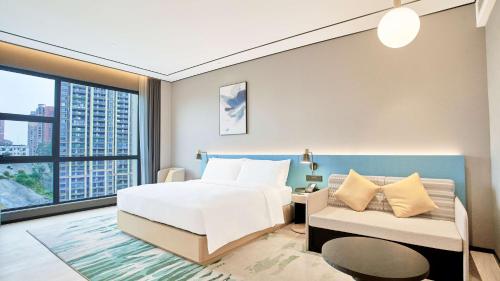 a hotel room with a bed and a couch at Hilton Garden Inn Chenzhou Beihu in Chenzhou