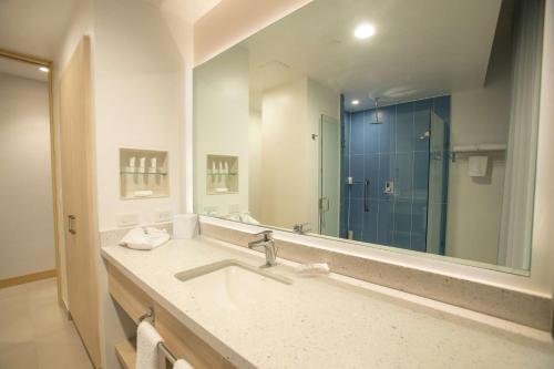 baño con lavabo y espejo grande en Hampton By Hilton Quito La Carolina Park, en Quito