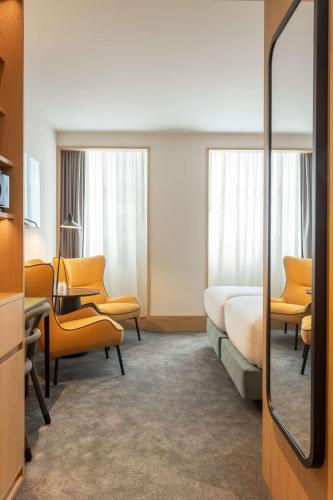 a hotel room with a bed and chairs and a mirror at Arts Hotel Porto, Tapestry Collection By Hilton in Porto