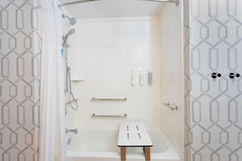 baño blanco con ducha y banco. en Hampton Inn Marianna I-10, en Marianna