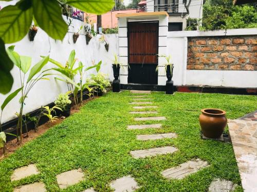 un jardín con una pasarela frente a una casa en Surewo Apartment, en Bentota