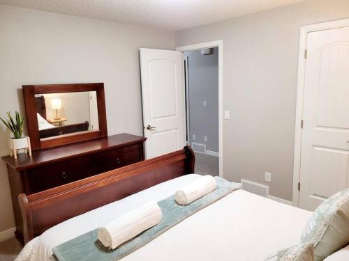 a bedroom with a bed with a dresser and a mirror at Mahogany Escape - Your Calgary Oasis in Calgary