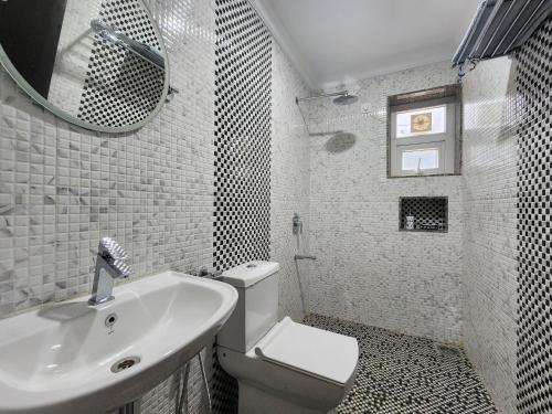 uma casa de banho com um lavatório, um WC e um espelho. em The Royal Oasis Goa em Majorda