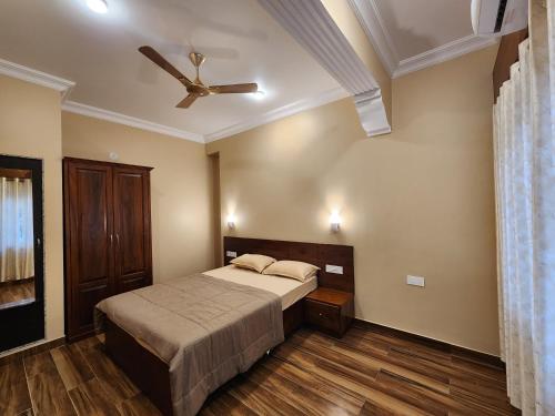 The Royal Oasis Goa في ماجوردا: غرفة نوم بسرير ومروحة سقف
