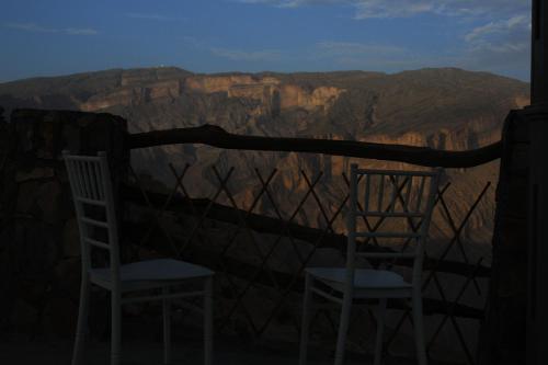 two chairs sitting on a balcony overlooking the grand canyon at Al khitaym guest house in Sa‘ab Banī Khamīs