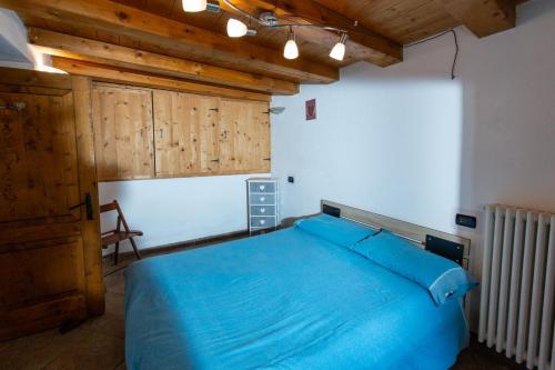 a bedroom with a blue bed and a wooden ceiling at SWEET TERRACE in Arvier