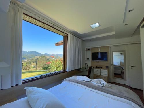 a bedroom with a bed and a large window at Casa Branca Pousada in Pomerode