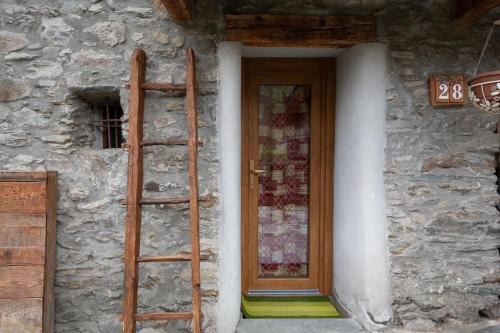 a ladder next to a stone building with a door at SWEET TERRACE in Arvier