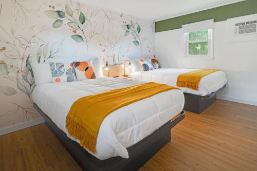 - une chambre avec 2 lits avec des draps orange et blancs dans l'établissement Birches Motel, à Saratoga Springs