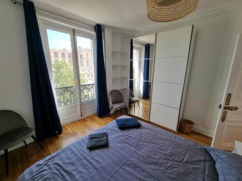 een slaapkamer met een bed en een groot raam bij Face château St Germain en Laye, appartement 4 à 6 personnes, 23 min de Paris Champs-Elysées in Saint-Germain-en-Laye