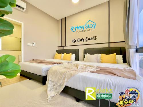 two beds in a bedroom with a sign on the wall at The Apple Residence By Heystay Management in Melaka