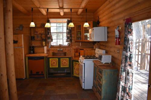 a kitchen in a log cabin with a stove at Sky Cabin in Ruidoso