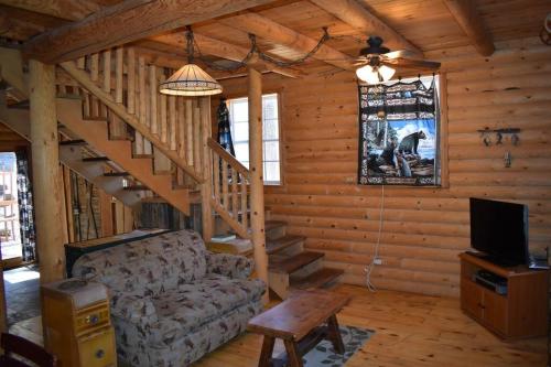 a living room with a couch and stairs in a cabin at Sky Cabin in Ruidoso